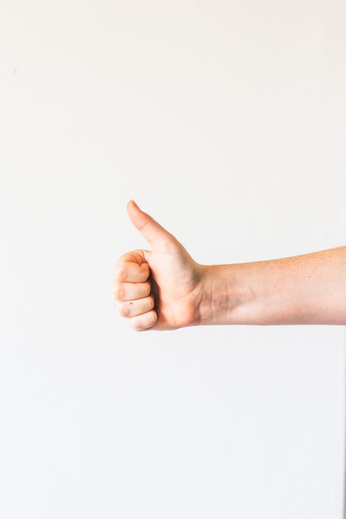 A person's arm and hand giving a thumbs-up gesture.