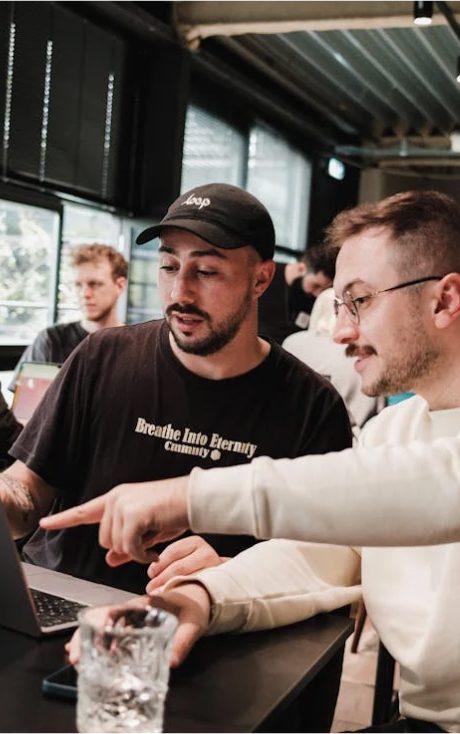 Two men look at a laptop, one points at the screen